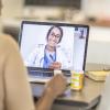 african american woman in telehealth video call with her doctor on her laptop