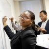 young adult african american woman in suit writing on a white board