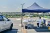 car pulling up to outdoor vaccine tent in a parking lot with clinicians